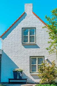 a house with two windows and a bench in front of it at Bed en Bike Texel in Den Burg