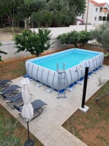- une piscine avec des chaises et une baignoire blanche dans l'établissement Apartment Ante, à Bibinje