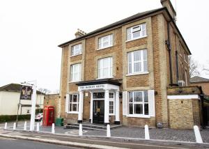 um edifício de tijolos com uma cabine telefónica vermelha em frente em The Hadley Hotel em New Barnet