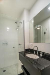 a bathroom with a sink and a glass shower at Studio Central e Completo - AYN011 in Curitiba
