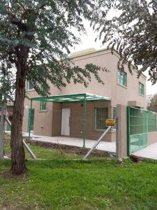 a building with a green fence and a tree at Melo 2203 Duplex 1 in Belén de Escobar