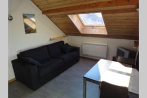 a living room with a black couch and a window at Loue studio de vacances rénové à Névache in Névache