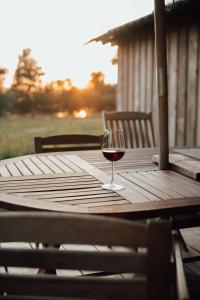 a glass of red wine sitting on a wooden table at Uz salas in Dagda