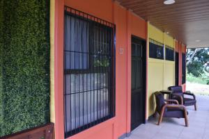 a building with black doors and chairs on a porch at Hotel Arenal Country Inn in Fortuna