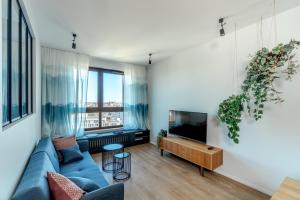 a living room with a blue couch and a tv at UP'arts in Wrocław