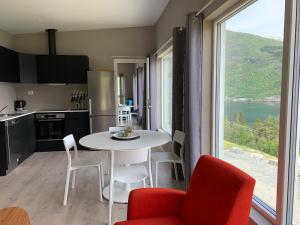 eine Küche mit einem Tisch und Stühlen sowie einem großen Fenster in der Unterkunft Olden Fjord Apartments in Olden