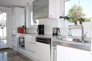 uma cozinha branca com um lavatório e um fogão em FeWo Bayha "Lerchenhaus" em Langenargen