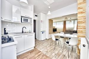 ペーチにあるPanoráma City Apartmanの白いキャビネット、テーブルと椅子付きのキッチンが備わります。