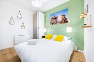 ein Schlafzimmer mit einem großen weißen Bett mit gelben Kissen in der Unterkunft Gare / 2 chambres / Appartistic Machines de l île / WIFI FIBRE in Nantes