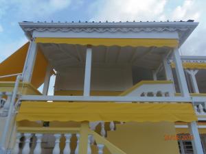 a yellow building with birds sitting on a balcony at Villa Mancina in Capesterre-Belle-Eau