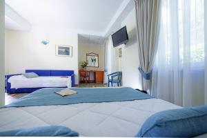 a bedroom with two beds and a desk and a window at Hotel Della Baia in Portovenere