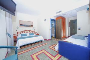 a bedroom with two beds and a tv and a couch at Hotel Della Baia in Portovenere +37 photos