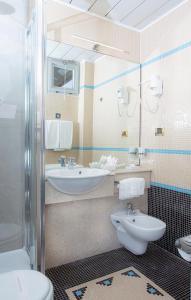 a bathroom with two sinks and a toilet and a mirror at Hotel Della Baia in Portovenere