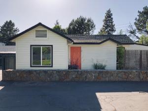 a white house with a stone wall and a red door at Sonoma's Best Guest Cottages in Sonoma