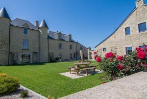 - une table de pique-nique devant un bâtiment avec des roses dans l'établissement Domaine de kerbillec, à Theix