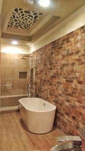a bath tub in a bathroom with a brick wall at Hotel Aurora in Antigua Guatemala