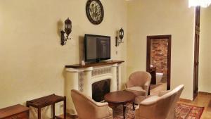 a living room with a fireplace with chairs and a tv at Hotel Aurora in Antigua Guatemala
