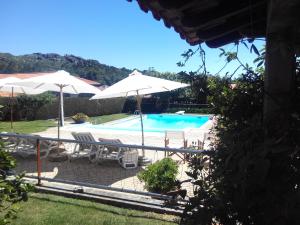 a swimming pool with umbrellas and chairs and a pool at Casa Paz do Outeiro in Paredes de Coura
