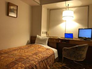 a hotel room with a bed and a desk with a laptop at Hotel New Green in Nagaoka