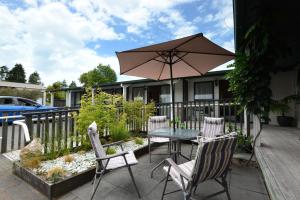 une terrasse avec une table, des chaises et un parasol dans l'établissement Goldmine Motel, à Waihi