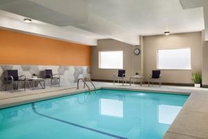 a pool in a hotel room with chairs and tables at La Quinta by Wyndham Salem OR in Salem