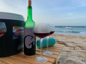 two glasses of wine sitting next to a bottle of wine at Cimarron Suites Playa Parguito in Aricagua