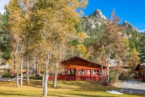 une cabane dans les montagnes avec des arbres au premier plan dans l'établissement Streamside on Fall River, à Estes Park