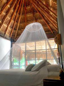 a bedroom with a bed with a thatched roof at Tunich Jungle Cabañas in Tulum