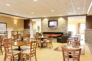 a restaurant with tables and chairs and a fireplace at Vegreville Suites in Vegreville