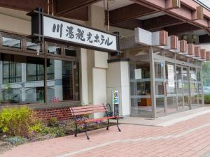 un banco frente a un edificio con un cartel en Kawayu Kanko Hotel, en Teshikaga