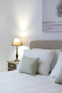 a bed with white pillows and a lamp on a table at Areti InCreteble Cretan Residences Collection in Sitia
