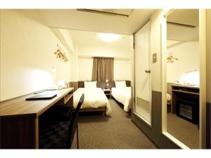 a hotel room with a bedroom with a desk and a bed at Sendai Business Hotel Ekimae in Sendai