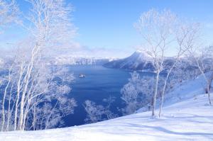 vistas a un lago en la nieve con árboles en Kawayu Kanko Hotel, en Teshikaga