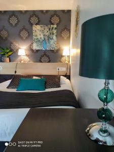 a bedroom with a bed with a green lamp on a table at Celtic Hotel in Auray