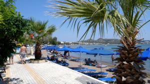 a beach with blue umbrellas and people on the beach at Lisabeth Apartments in Faliraki