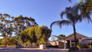 a car parked in front of a building with palm trees at Renmark Country Club in Renmark