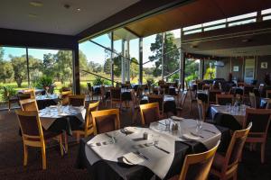 Un comedor con mesas y sillas y ventanas. en Renmark Country Club, en Renmark