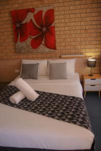 um quarto com uma cama com flores vermelhas na parede em Squatters Homestead Motel em Casino