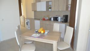 uma cozinha com uma mesa de madeira e cadeiras com frutas em Akrotiria Beach Apart Complex em Nessebar