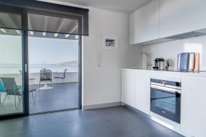 a kitchen with white cabinets and a table with chairs at Blue Frames Summer House in Andros