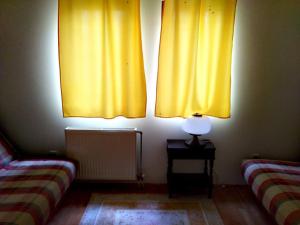 a room with two beds and yellow curtains at Milica in Zlatibor
