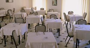 ポリコーロにあるHeraclea Hotel Residenceのテーブルと椅子(白いテーブルクロス付)が備わる部屋