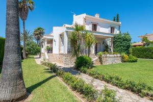 ein großes weißes Haus mit Palmen und Gras in der Unterkunft Can Llorens in Pollença