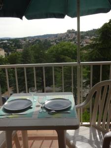 einen Tisch mit zwei Gläsern und einem Sonnenschirm auf dem Balkon in der Unterkunft Résidence les chênes blancs Appartement T2 in Gréoux-les-Bains