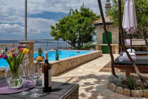 a table with a bottle of wine and flowers next to a swimming pool at Villa Sukara in Makarska