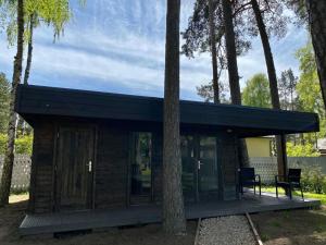 a cabin in the woods with two chairs and a tree at Pine Resort in Saulkrasti