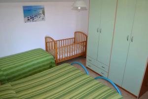 ein Schlafzimmer mit einem Bett, einem Kinderbett und einem Schrank in der Unterkunft Marina's apartment Ogliastra in Lotzorai