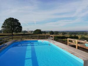 une piscine avec une terrasse en bois et une piscine bleue dans l'établissement Domaine de La Madeleine, à Ygrande