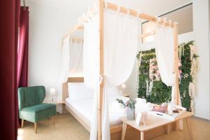 1 dormitorio con cama con dosel y silla verde en Na'maste Apartments en Atenas