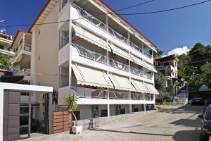 a white apartment building with balconies on a street at Anesis Hotel in Neos Marmaras